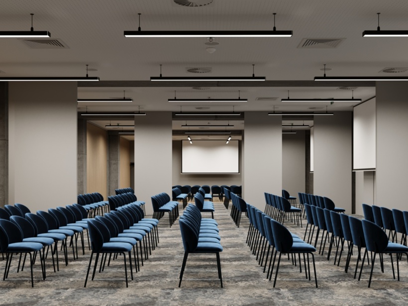 Rząd krzeseł ustawionych w przestrzennej sali konferencyjnej z rzutnikiem w tle