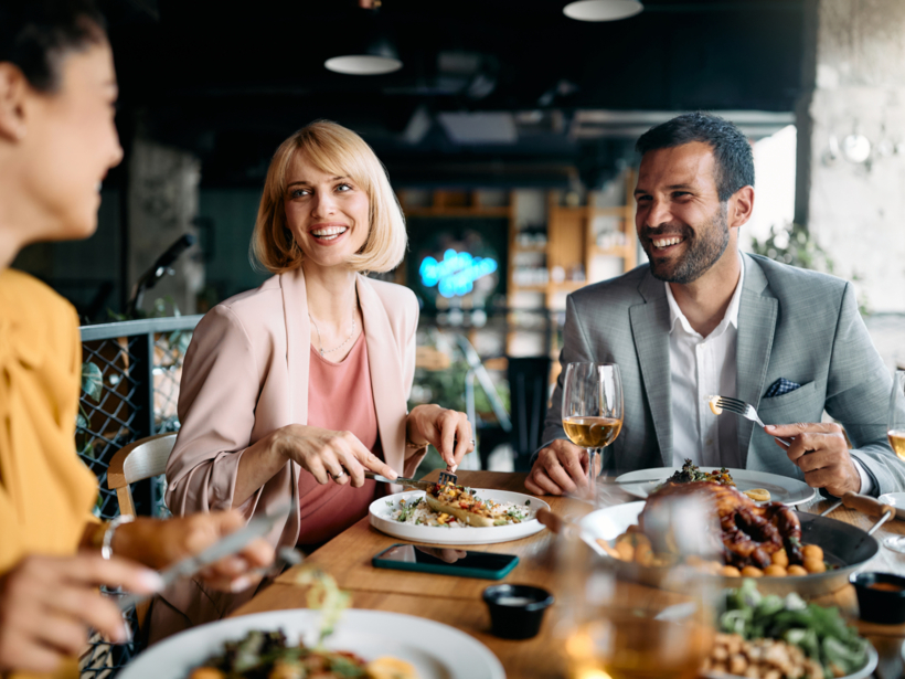Radośni, żywo dyskutujący goście w restauracji hotelowej przy spożywaniu zamówionych posiłków