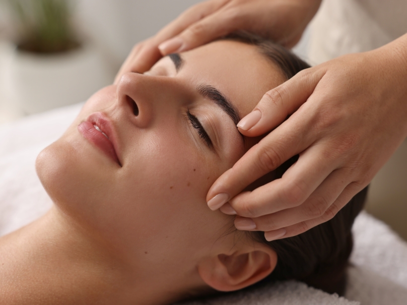 Masaż skroni relaksującej się kobiety w strefie wellness