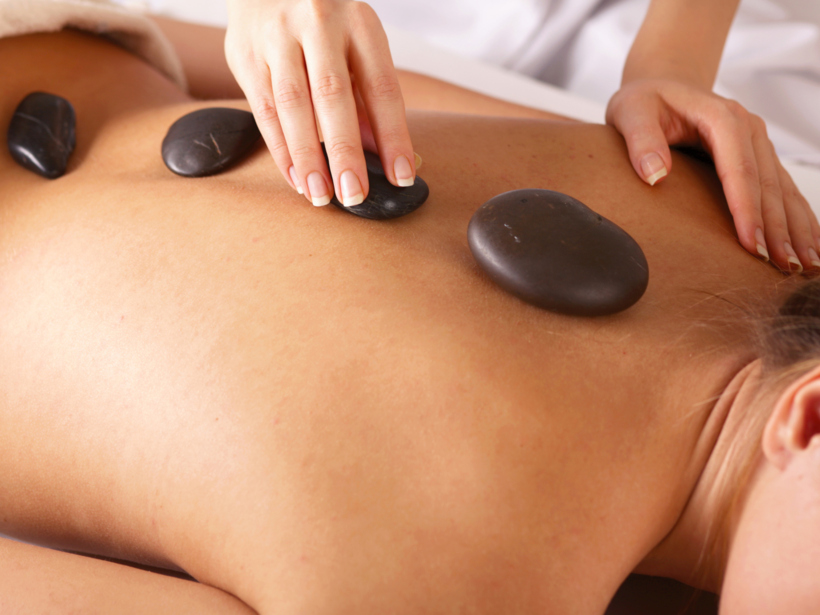 Kobieta układa kamienie na plecach gościa w strefie wellness hotelu