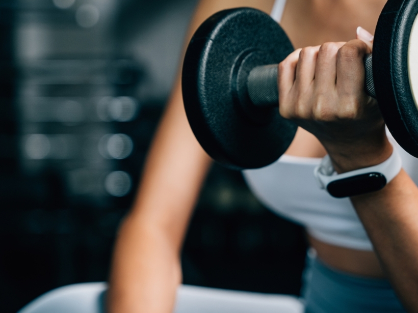 Kobieta wykonuje ćwiczenie z hantlami w strefie fitness
