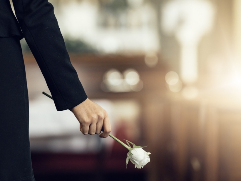 Elegancka kobieta w czarnej sukience niosąca białą różę