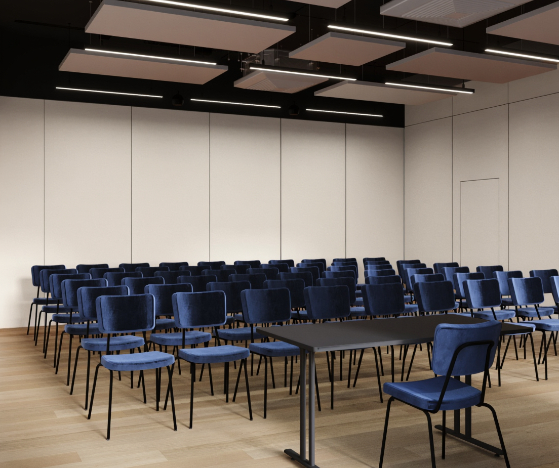 Sala konferencyjna z rzędami granatowych krzeseł, stołem prelegenta, drewnianą podłogą i akustycznym sufitem.