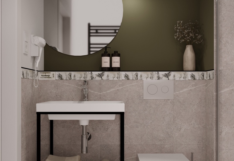 Mała łazienka hotelowa: zielona ściana z okrągłym lustrem, wisząca lampa, umywalka z kosmetykami, ręczniki, nowoczesna toaleta.