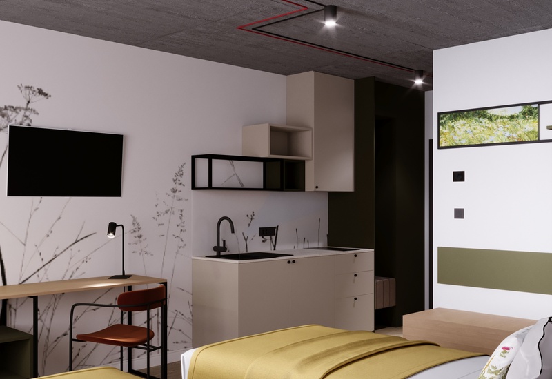Nowoczesne studio z aneksem kuchennym, dwoma łóżkami w żółtych narzutach, biurkiem, telewizorem i betonowym sufitem.