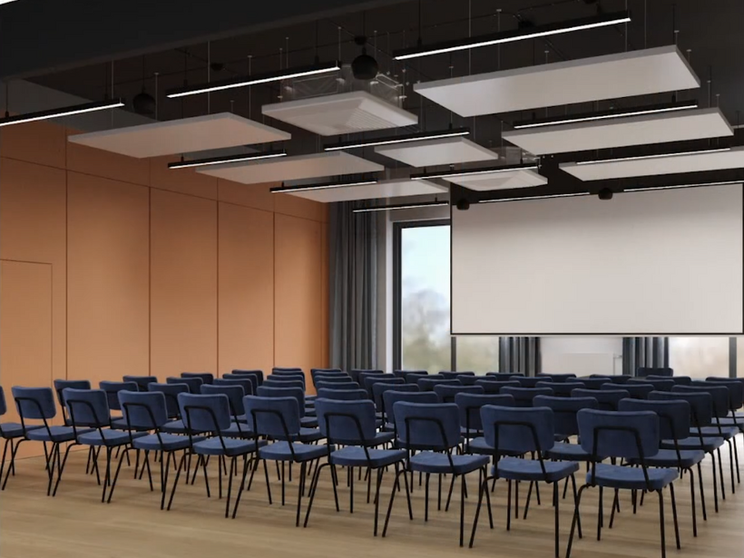 Sala konferencyjna z rzędami niebieskich krzeseł, dużym ekranem, drewnianą podłogą i nowoczesnymi panelami sufitowymi.