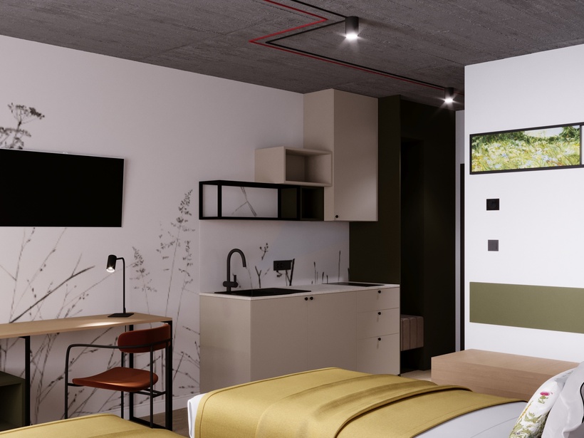 Nowoczesne studio z aneksem kuchennym, dwoma łóżkami w żółtych narzutach, biurkiem, telewizorem i betonowym sufitem.