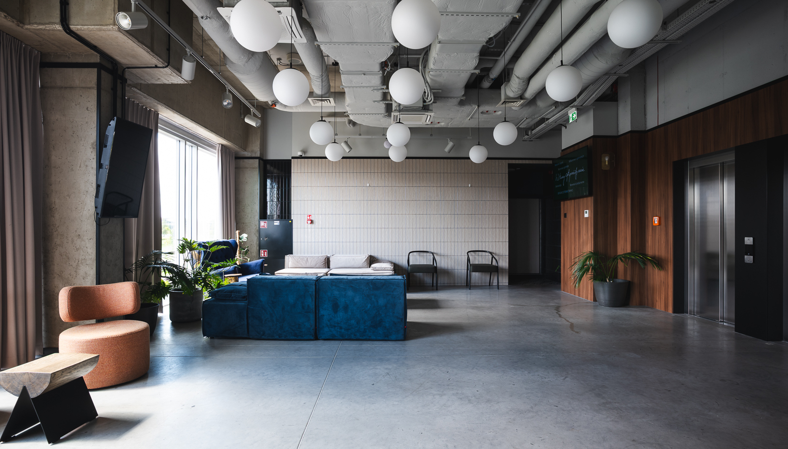 Nowoczesna lobby hotelowa z wygodnymi meblami, niebieską sofą, stołkiem, roślinami i eleganckim oświetleniem sufitowym