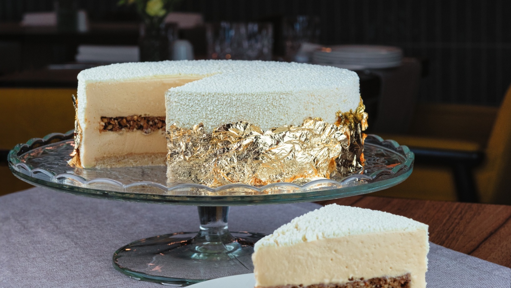 Luksusowy biały deser na szklanej paterze z jadalnym złotem i warstwą chrupiących orzechów