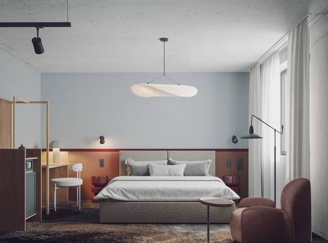 Nowoczesny pokój hotelowy z dużym łóżkiem, miękkim fotelem, biurkiem oraz minimalistycznym oświetleniem i zasłonami.