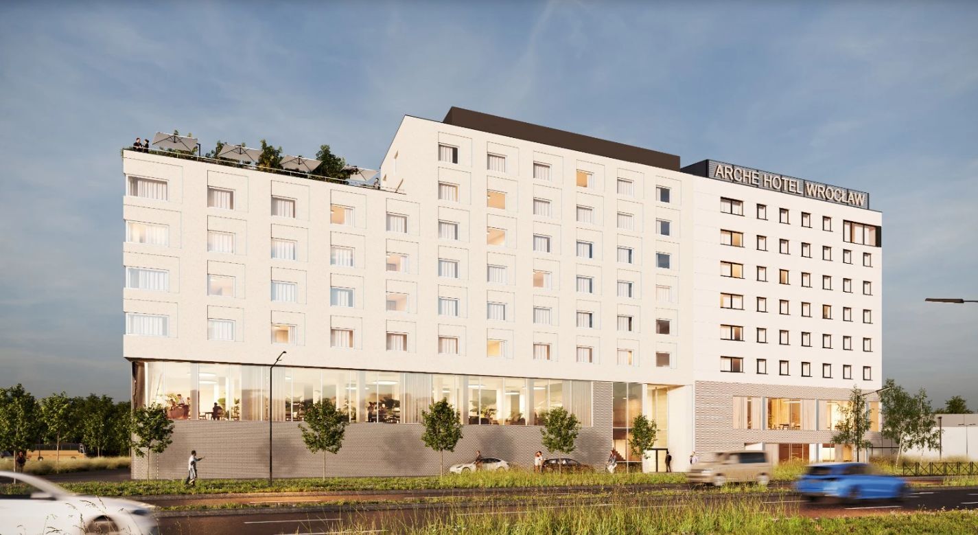 Nowoczesny hotel Arche Wrocław z tarasem na dachu, dużymi oknami i widocznym wejściem, położony przy ruchliwej ulicy.