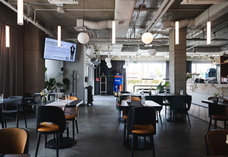 Modern hotel restaurant with minimalist furniture, unique pendant lighting, and courtyard views through large windows