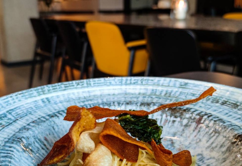 Artfully plated gourmet dish with crispy vegetable chips on a decorative plate in a stylish hotel restaurant.