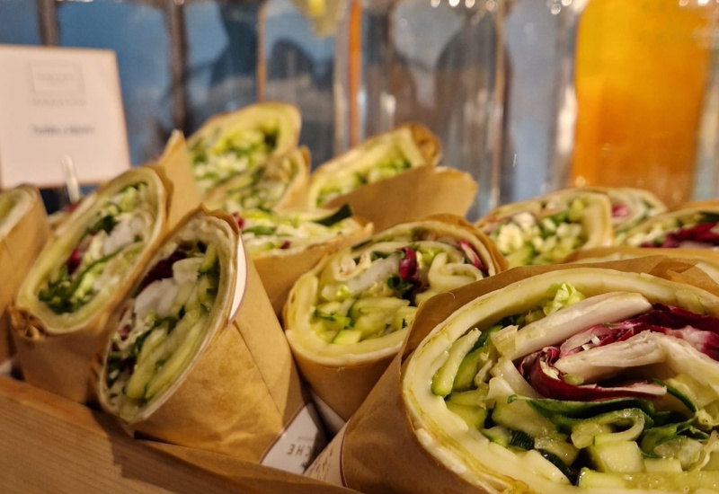 Fresh vegetable wraps with lettuce, cucumber, and cheese served on a wooden tray in a hotel café.