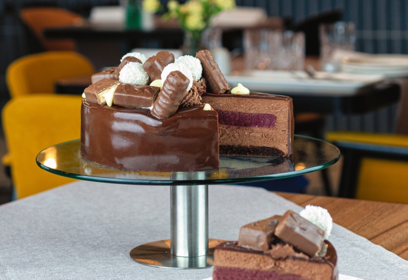 Chocolate cake on a glass stand in a stylish restaurant, topped with pralines and coconut balls