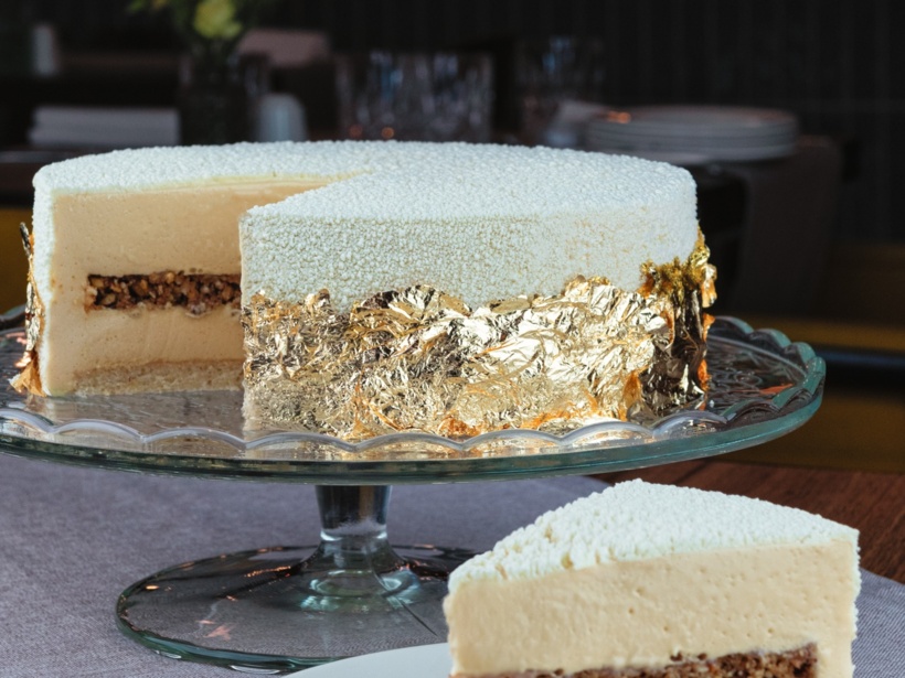 Luksusowy biały deser na szklanej paterze z jadalnym złotem i warstwą chrupiących orzechów