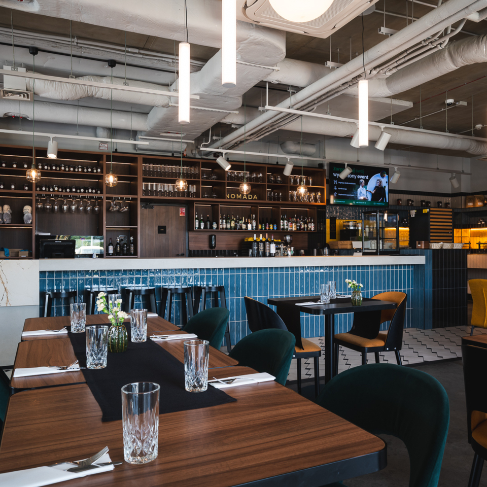 Nowoczesna restauracja hotelowa z baru z niebieskimi płytkami, wygodnymi krzesłami i eleganckimi dekoracjami na stołach