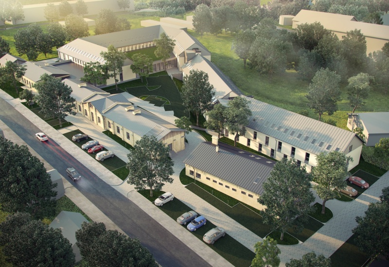 Low‑rise hotel wings with pitched metal roofs around a landscaped central courtyard, guest parking, walking paths and tree‑lined grounds.