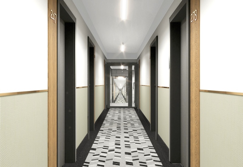 Carpeted hotel corridor with patterned runner, numbered room doors with wood frames, soft recessed ceiling lights and a mirror at the end.
