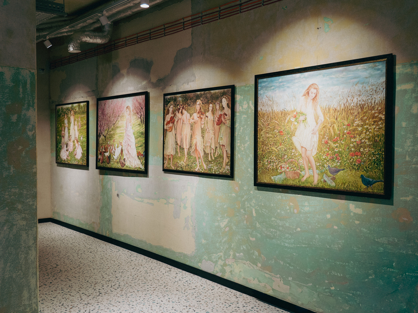 Boutique-Hotelflur mit gerahmten Landschaftsgemälden, abblätterndem Putz, Terrazzo-Boden und warmen Spotlights für eine intime Galerie-Atmosphäre.