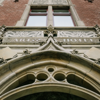 Ornate stone arch with carved 'ART HOTEL' signage, decorative mouldings and red-brick upper floors of a boutique hotel.