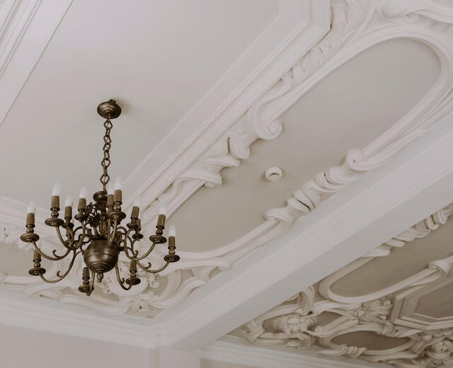 Bogato zdobiony sufit ze stiukową, barokową sztukaterią i mosiężnym żyrandolem, eleganckie wnętrze hotelowe