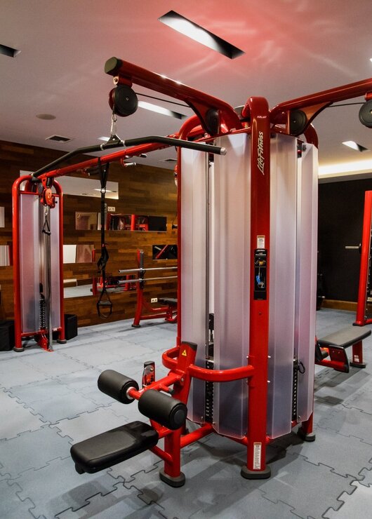 Nowoczesna siłownia hotelowa z profesjonalnym czerwonym sprzętem do ćwiczeń i lustrzaną ścianą dla pełnej kontroli treningu