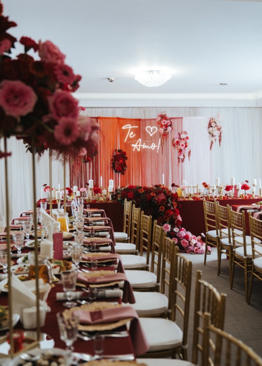 Eleganckie wnętrze sali bankietowej z czerwonymi dekoracjami i kwiatami, z napisem "Te Amo!" na tle
