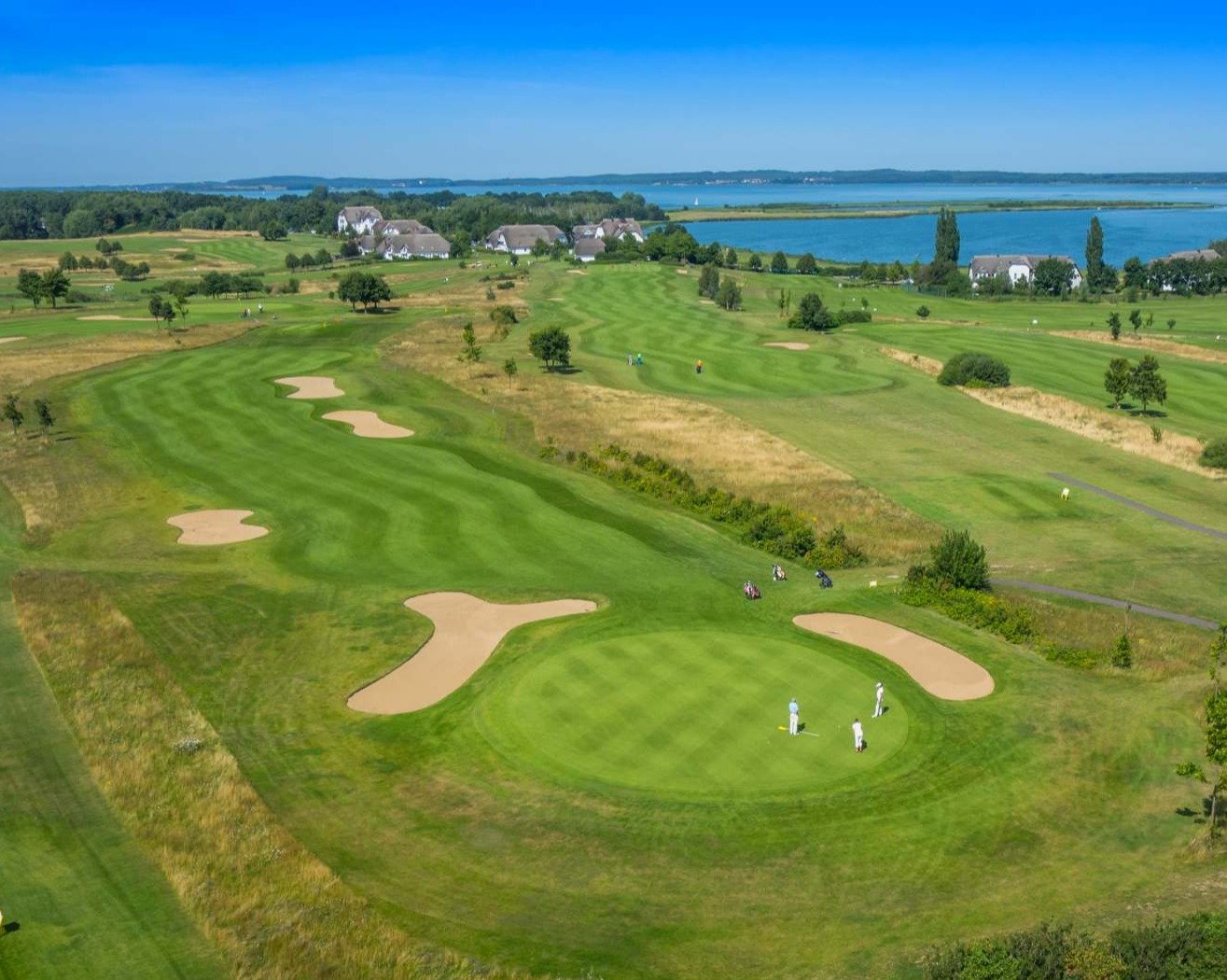 Blick über das Loch 17, gelber Platz, mit Ausblick auf das Resort & den Balmer See