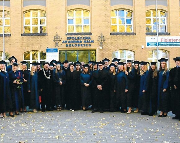 Absolventi v talárech a čepicích před budovou Společenské akademie věd v Kołobřehu