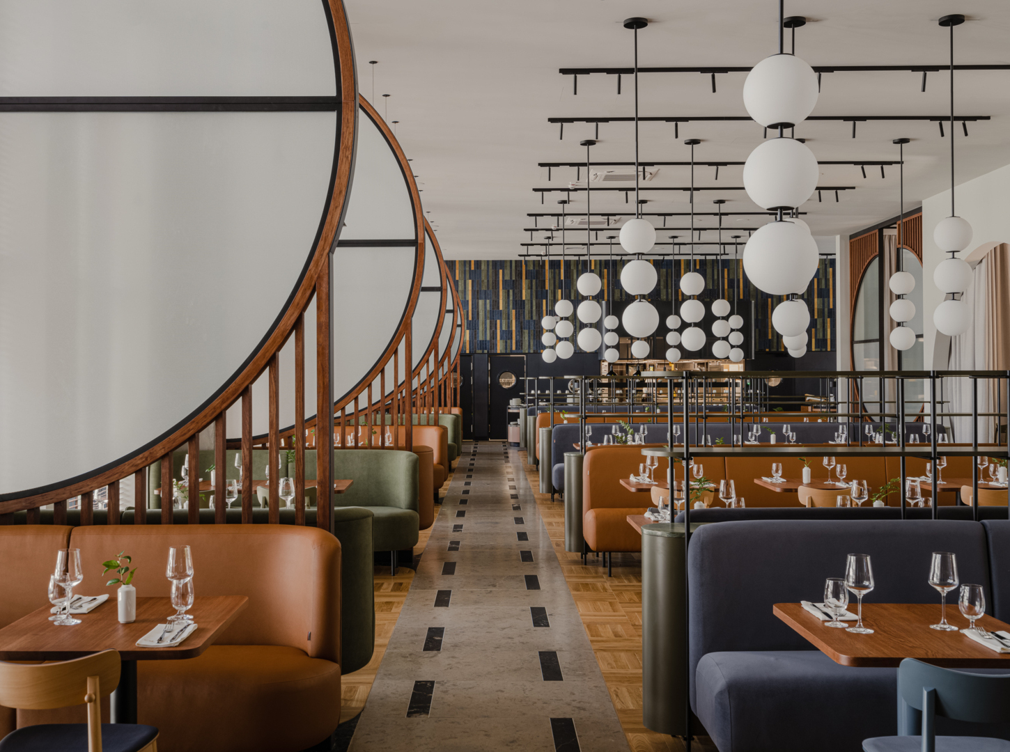 Nowoczesna restauracja hotelowa z łukowymi drewnianymi przegrodami, skórzanymi i aksamitnymi lożami, kulistymi lampami i nakrytymi stolikami