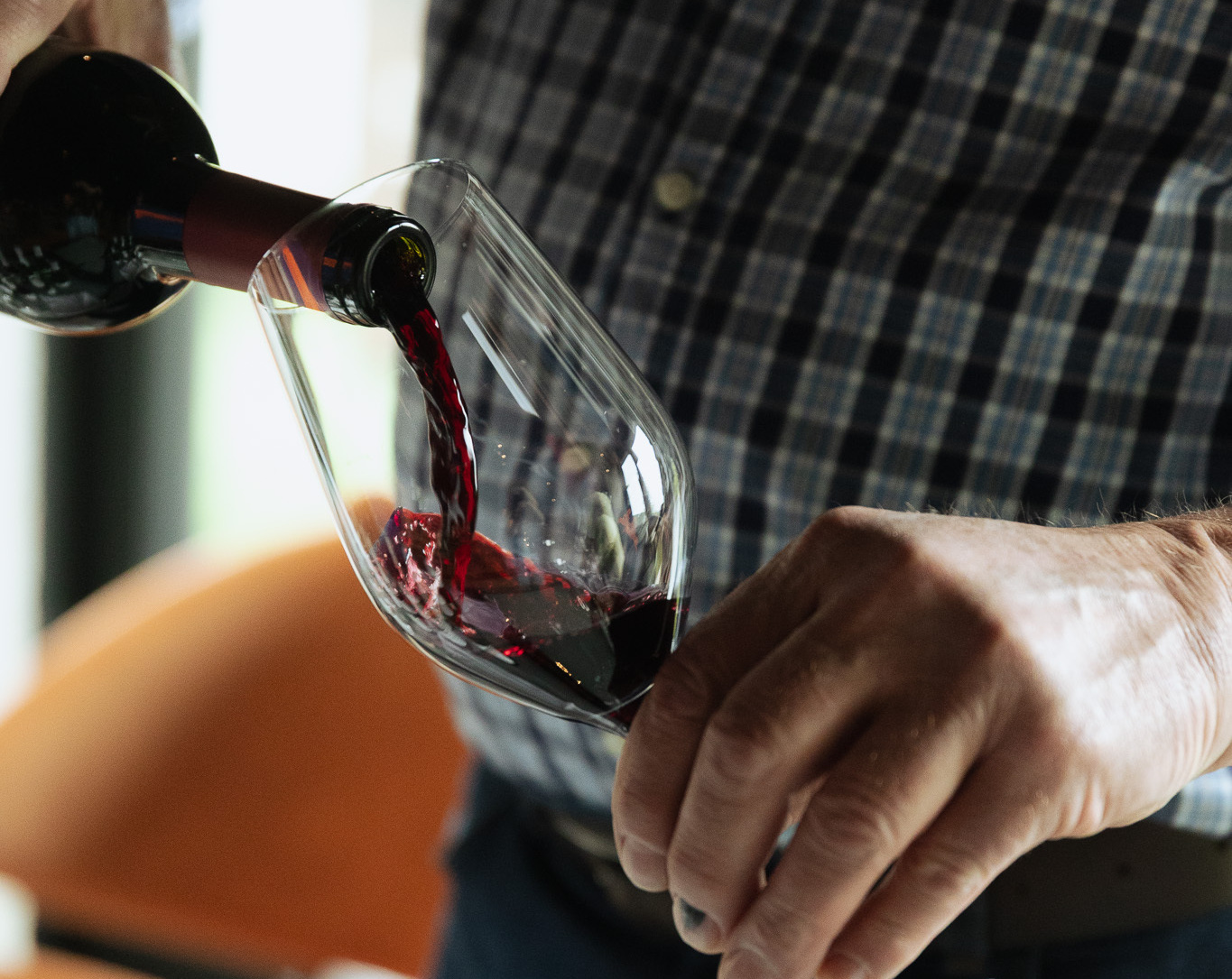 Kelner nalewa czerwone wino do kieliszka; zbliżenie na dłonie, butelkę i serwowanie.