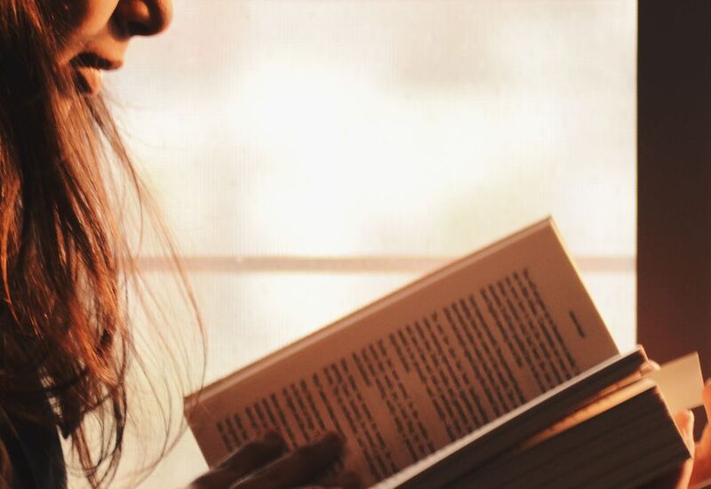 Vendég egy könyvet olvas egy otthonos hotel szobában, meleg, lágy természetes fényben, csendes légkörben.