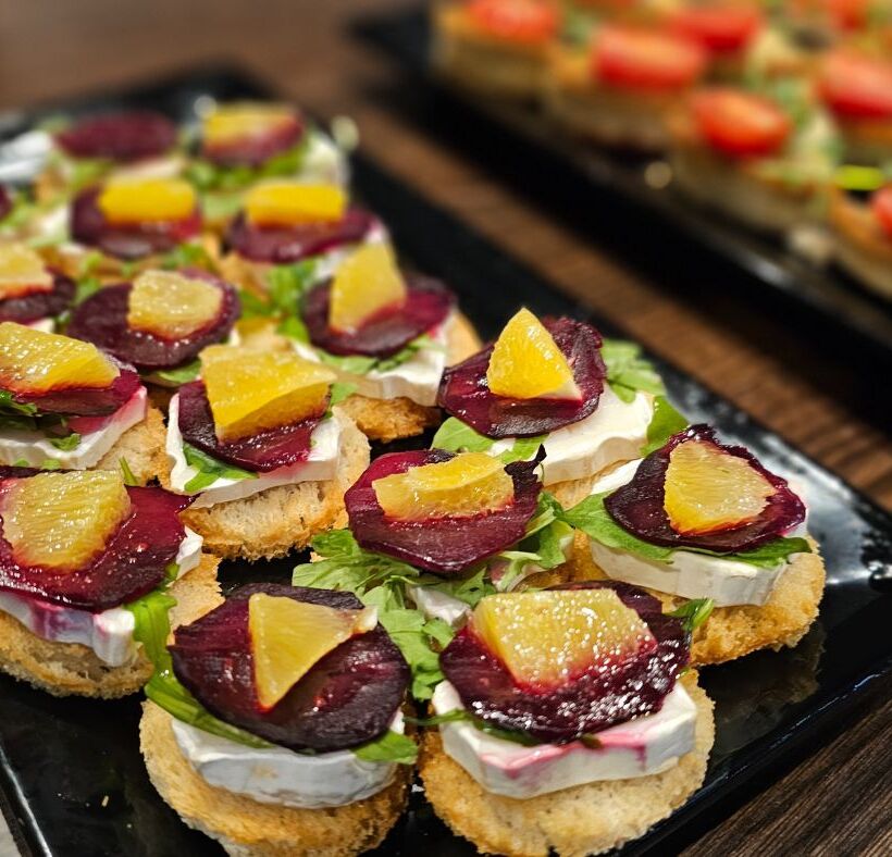 Elegant canapés with bread rounds, cheese, lettuce, beet slices, and orange segments, perfect for hotel events and receptions.