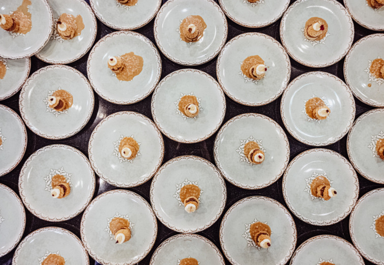 Elegant plates with cookie desserts topped with cream and caramel sauce, arranged for a hotel banquet or event.