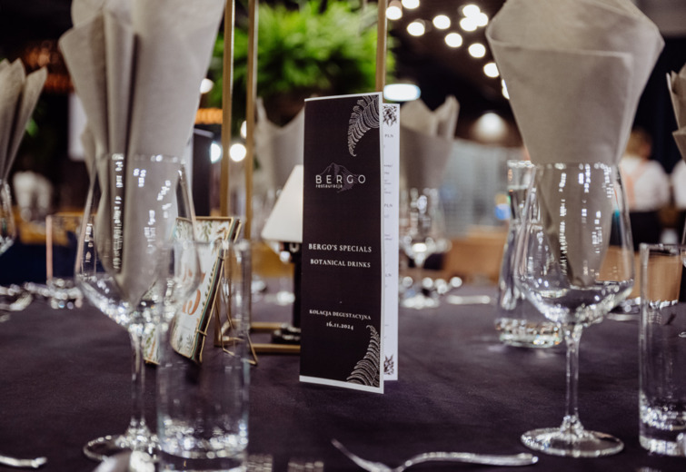 Elegantly set restaurant table with menu featuring botanical drink specials, gold accents, and neatly folded napkins.