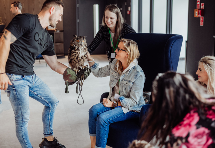 Hotelgast streichelt eine Eule, die von einem Mitarbeiter in der modernen Lobby gehalten wird