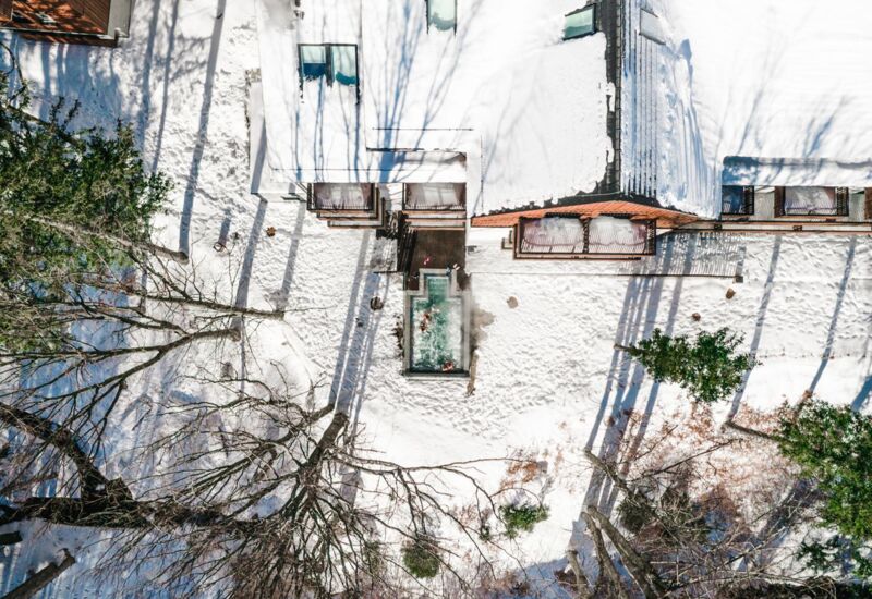 Hotel z zewnętrznym podgrzewanym basenem jacuzzi otoczonym śniegiem i zimowymi drzewami