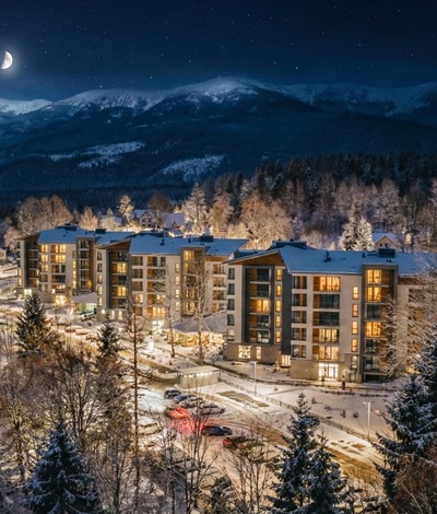 Verschneites Bergresort mit modernem Hotel, warm erleuchteten Zimmern, schneebedeckten Kiefern und mondbeschienenen Gipfeln.
