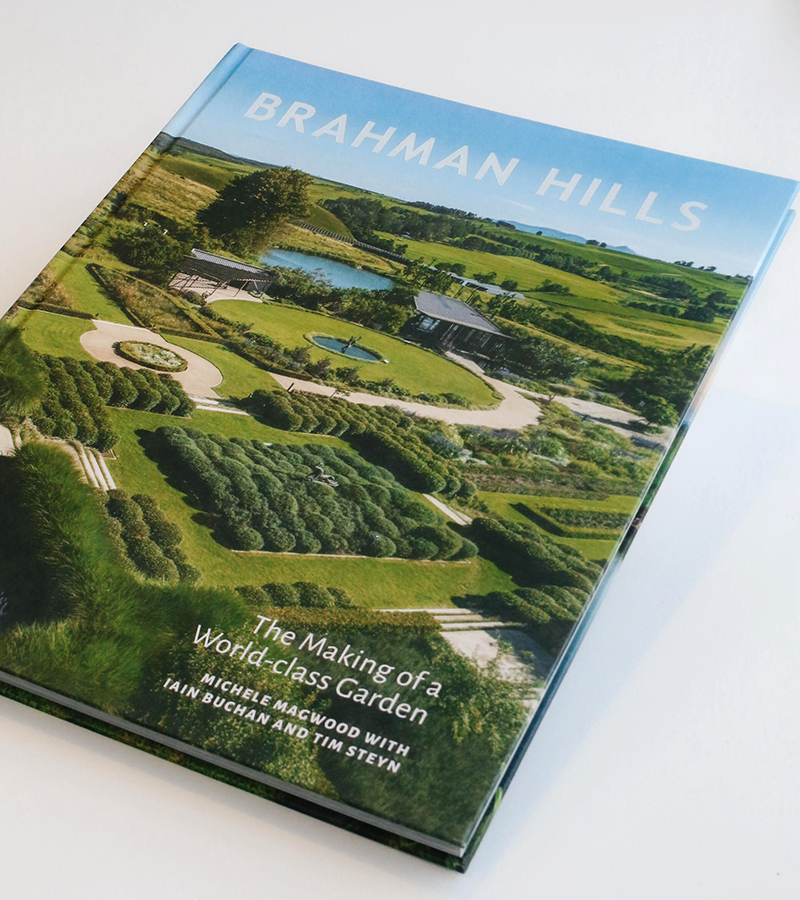 Brahman Hills hardcover showing aerial view of manicured parterre gardens, ponds and rolling green countryside.