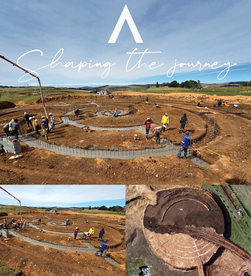 Curving spiral concrete foundations being poured by workers on a rural site, wide aerial and ground views of the construction
