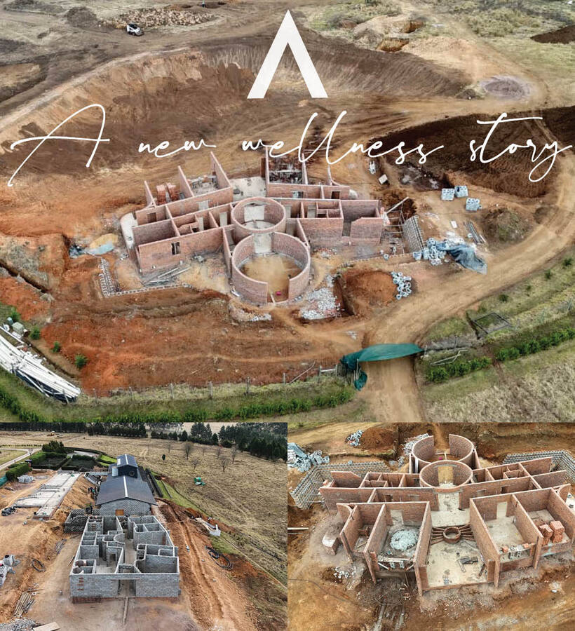 Aerial view of a wellness retreat under construction in a rural landscape, circular therapy rooms and new foundations visible