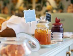 Breakfast setup with jars of honey and jam, fresh bread in basket, and retro green toaster on white countertop