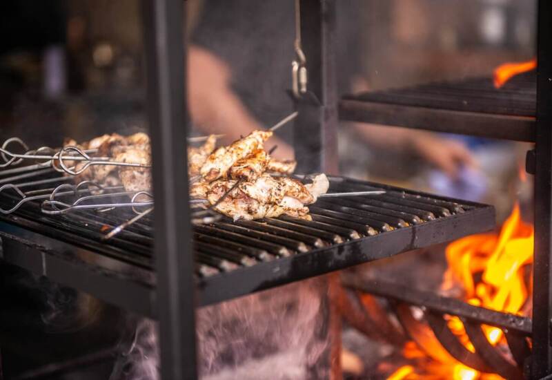 Skewers of seasoned chicken grilling over an open flame on a charcoal barbecue, capturing smoky outdoor cooking