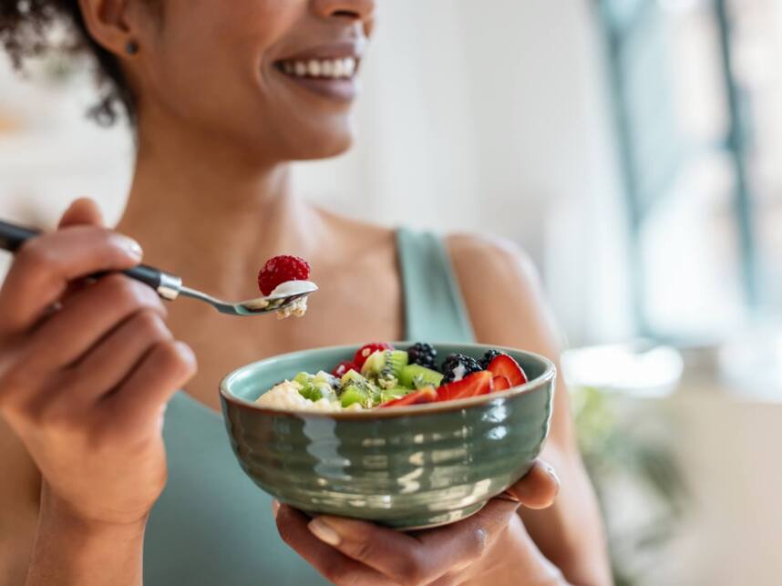 Guest enjoying a fresh fruit bowl with strawberries, kiwi, blackberries, raspberries, and creamy yogurt in a bright, airy breakfast setting
