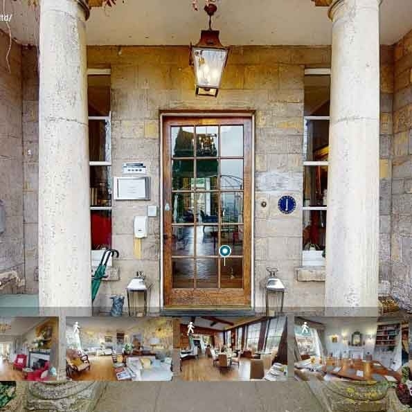 Stone entrance with tall columns and a glass-paneled wooden door leading to a hotel lobby with cozy seating inside.