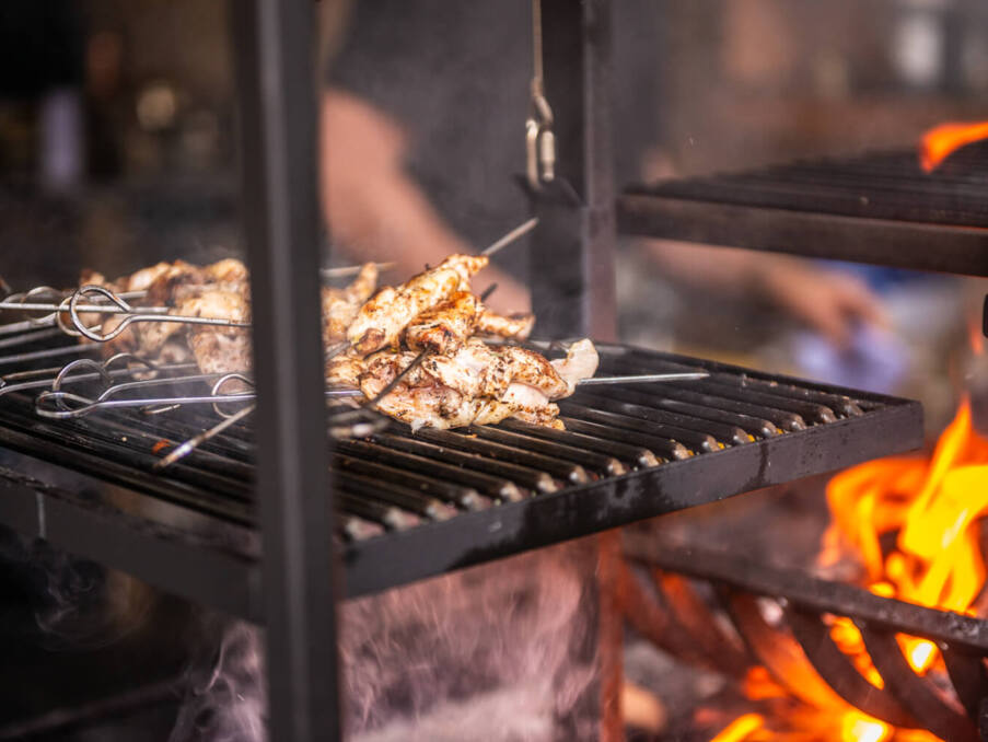 Chicken skewers grilling over an open flame on a metal grill, creating a smoky and sizzling aroma