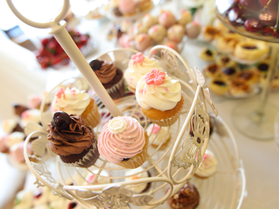 Delicate assorted cupcakes with various frosting and decorative flowers on an elegant white tiered stand