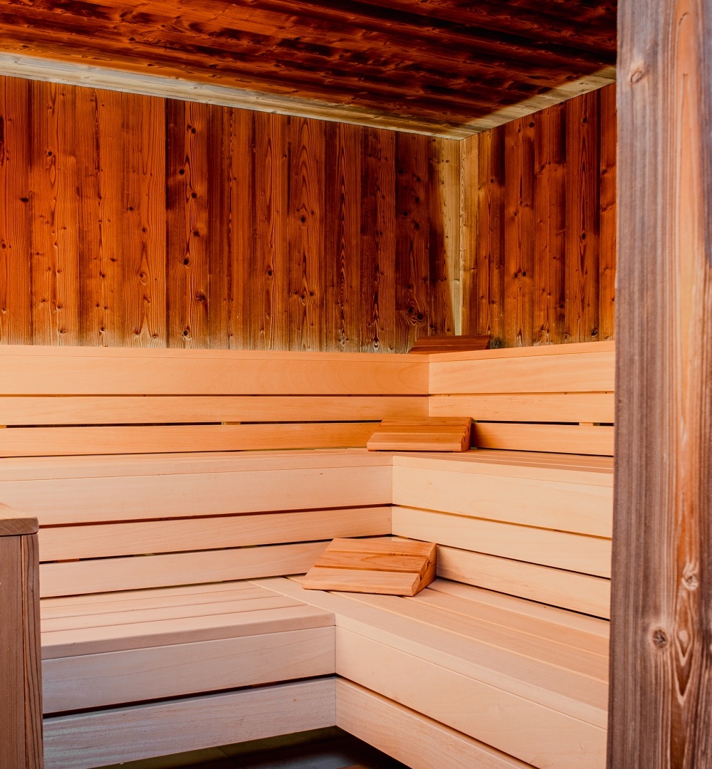 Przytulna sauna z jasnym drewnem, kamieniami do podgrzewania i ergonomicznymi oparciami dla relaksu gości