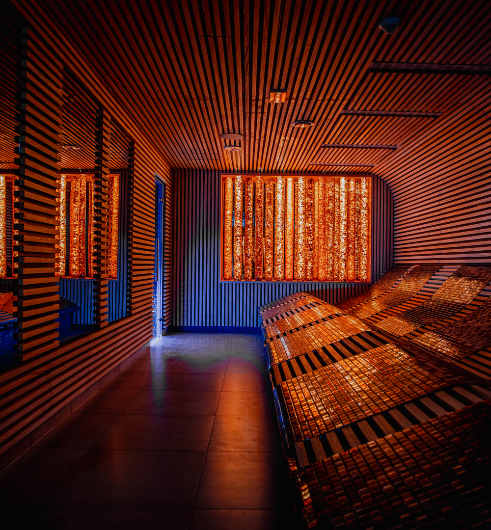 Przytulne pomieszczenie spa z podświetlanymi leżankami i nowoczesnym drewnianym wystrojem, idealne do relaksu